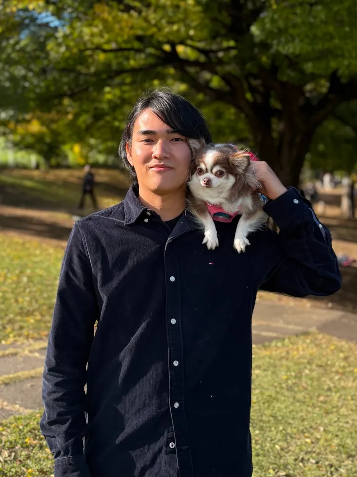 尾形光洋のプロフィール写真。公園で愛犬のチワワを肩に乗せている